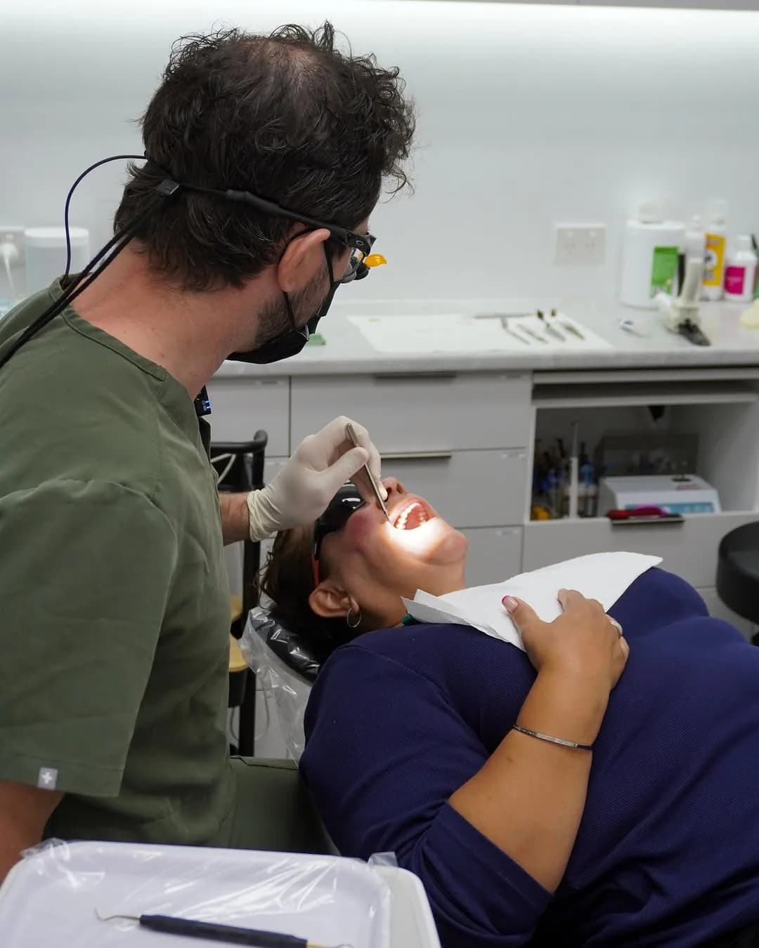 A dentist checking a patient’s teeth with a mirror and light during a check-up