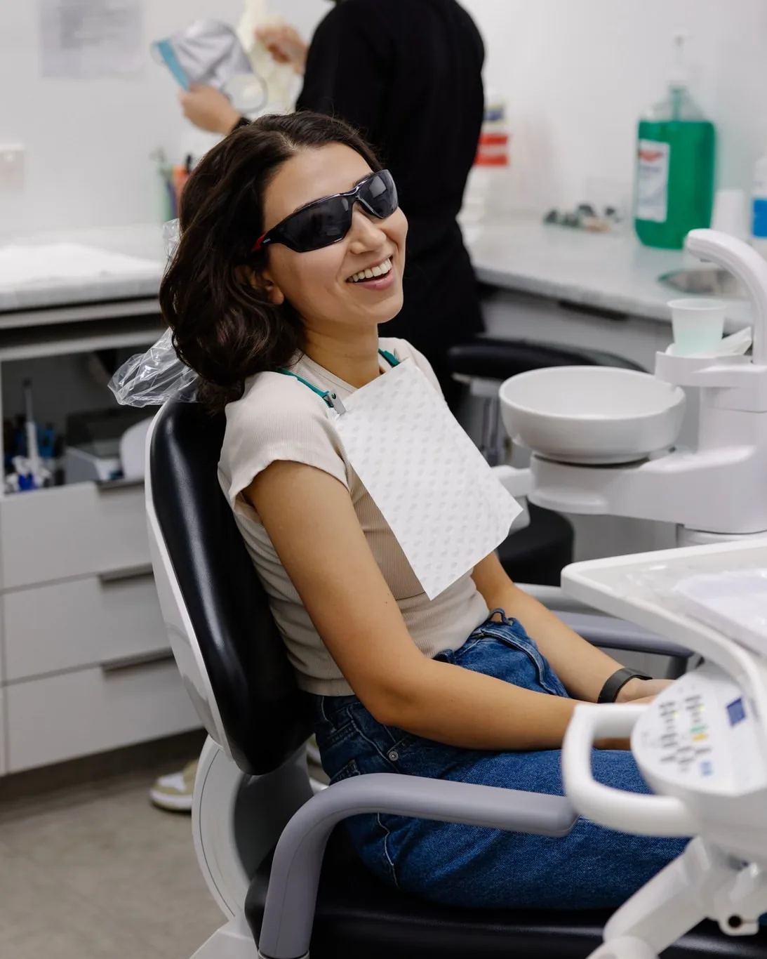 A patient laughing in the dental chair, wearing protective glasses