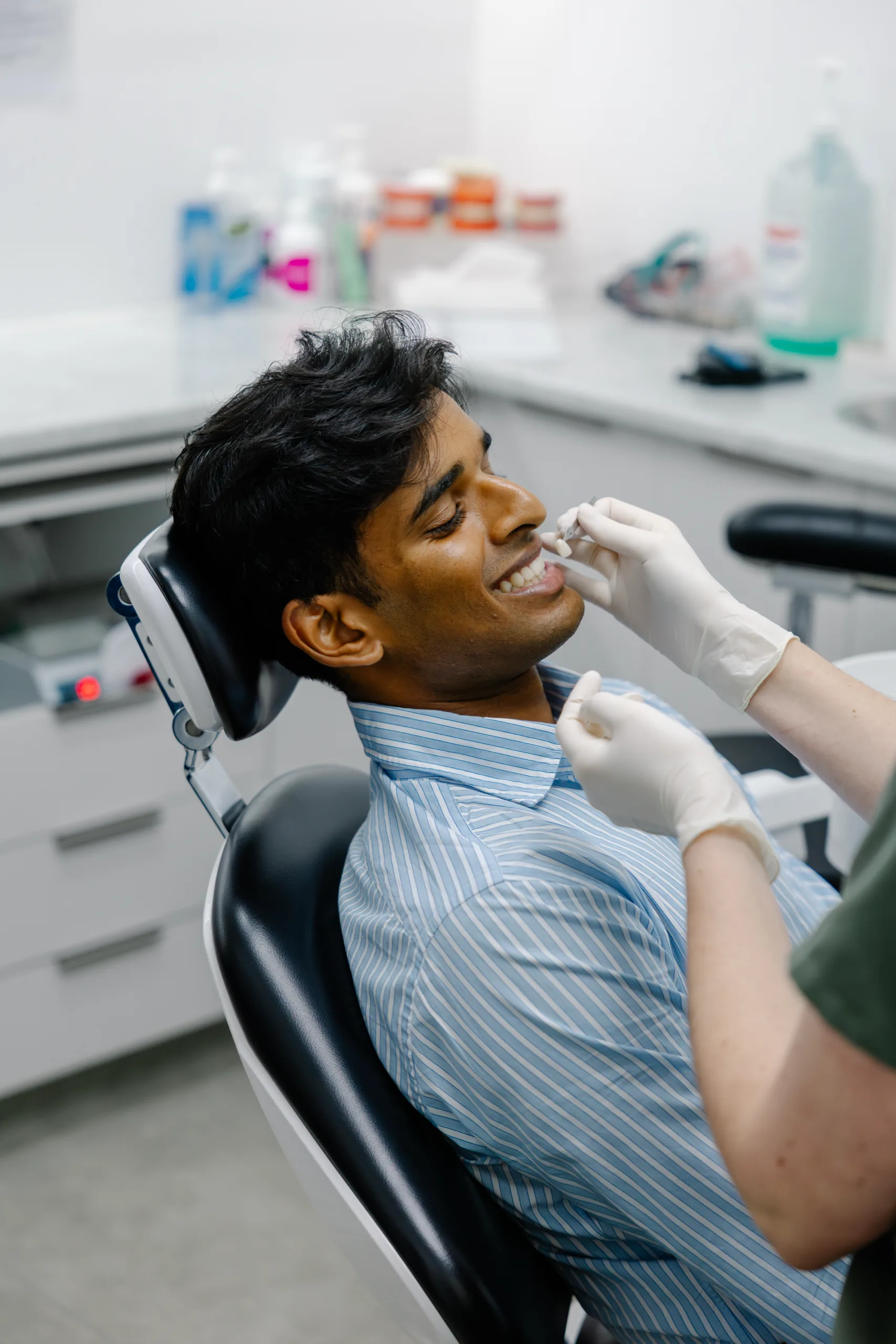 A patient smiling while a dentist matches a shade guide to his teeth