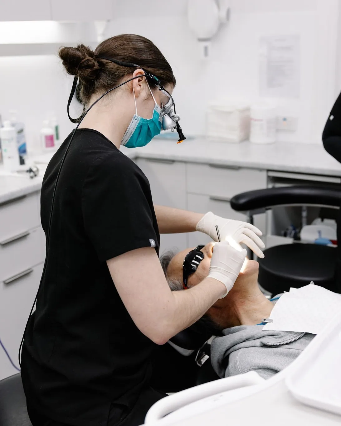 A dentist wearing loupes checking a patient’s teeth