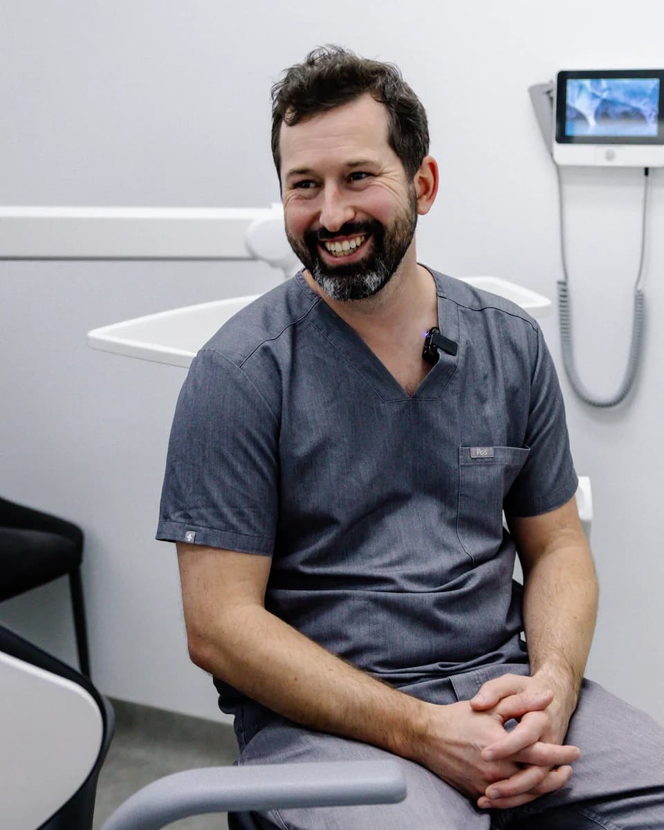 Dr James Pomfret in grey scrubs, laughing in the surgery