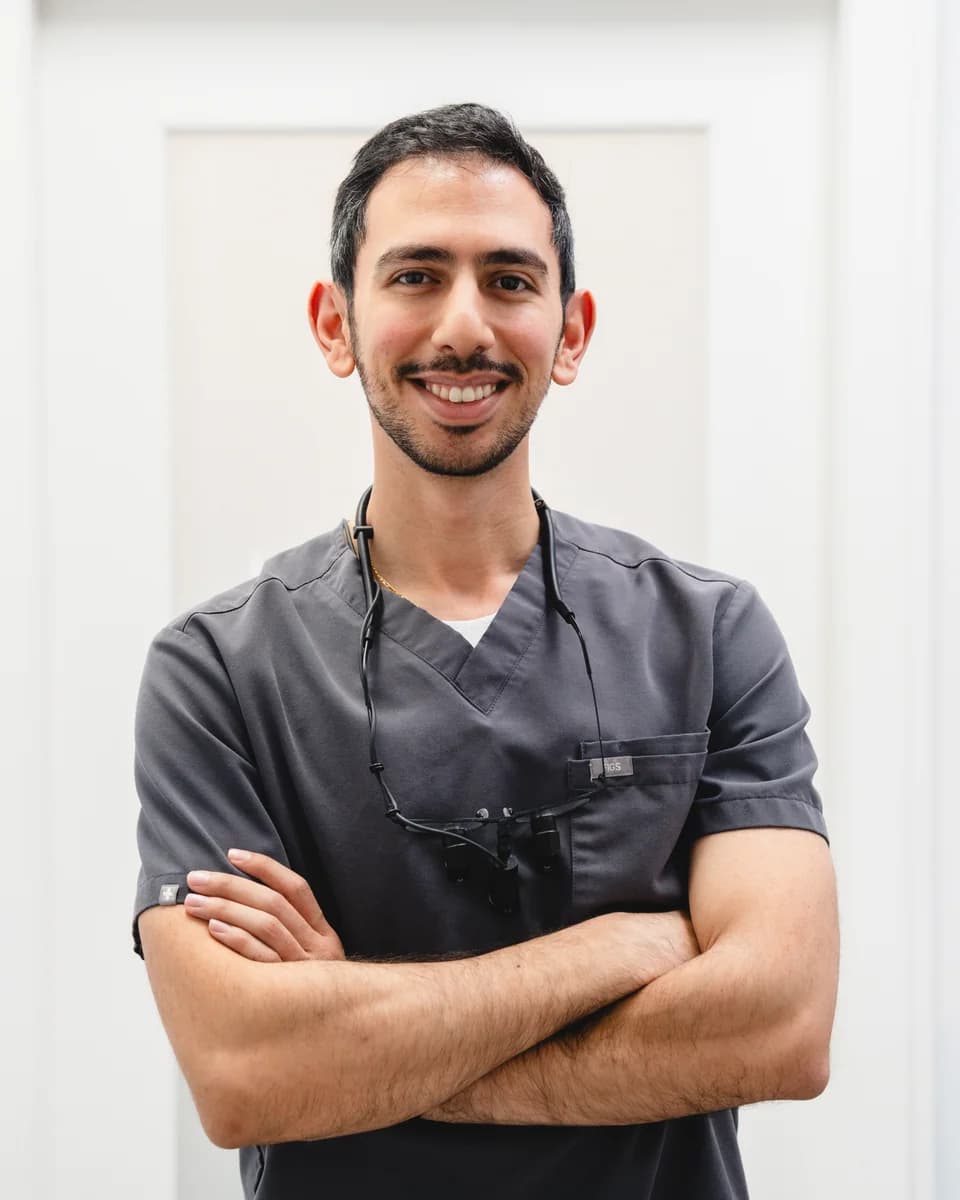 Dr Jose Shina in grey scrubs, arms crossed, smiling