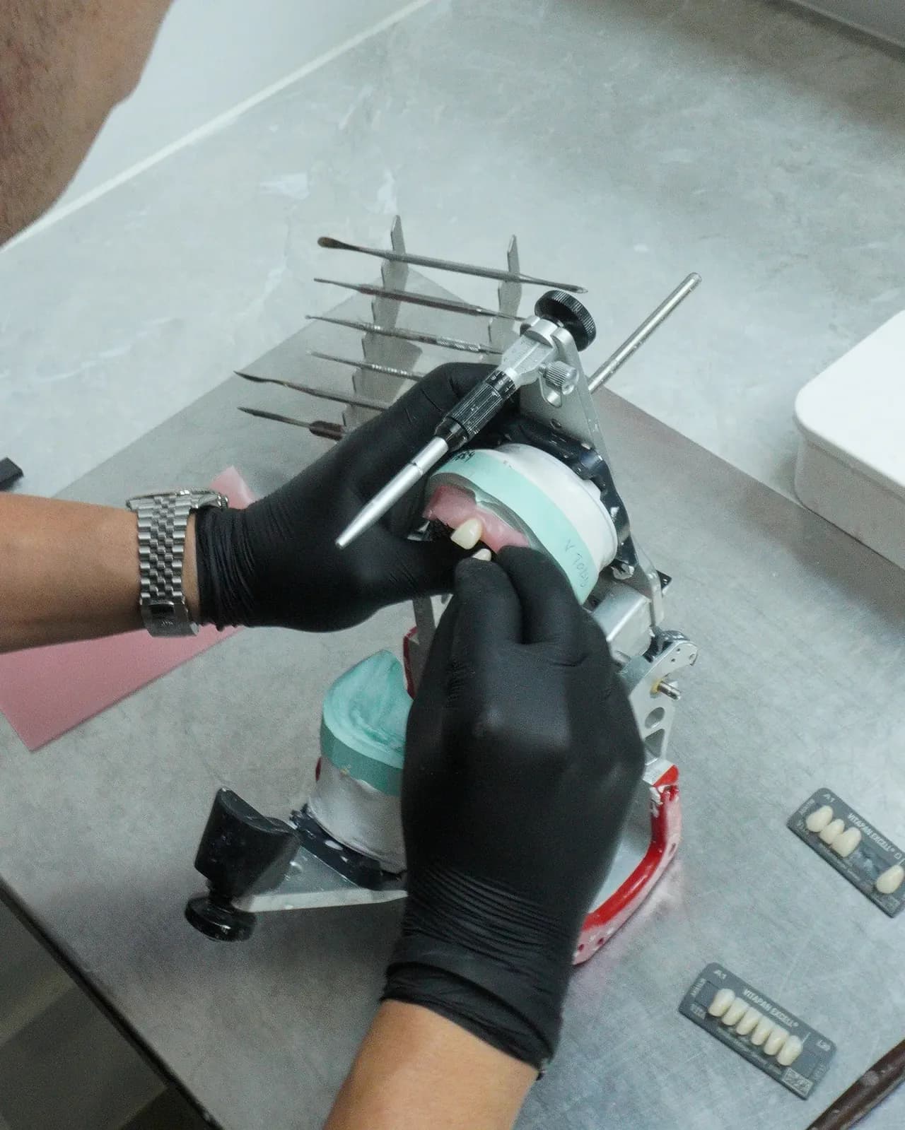Gloved hands setting denture teeth on a model in the Dental Spot lab