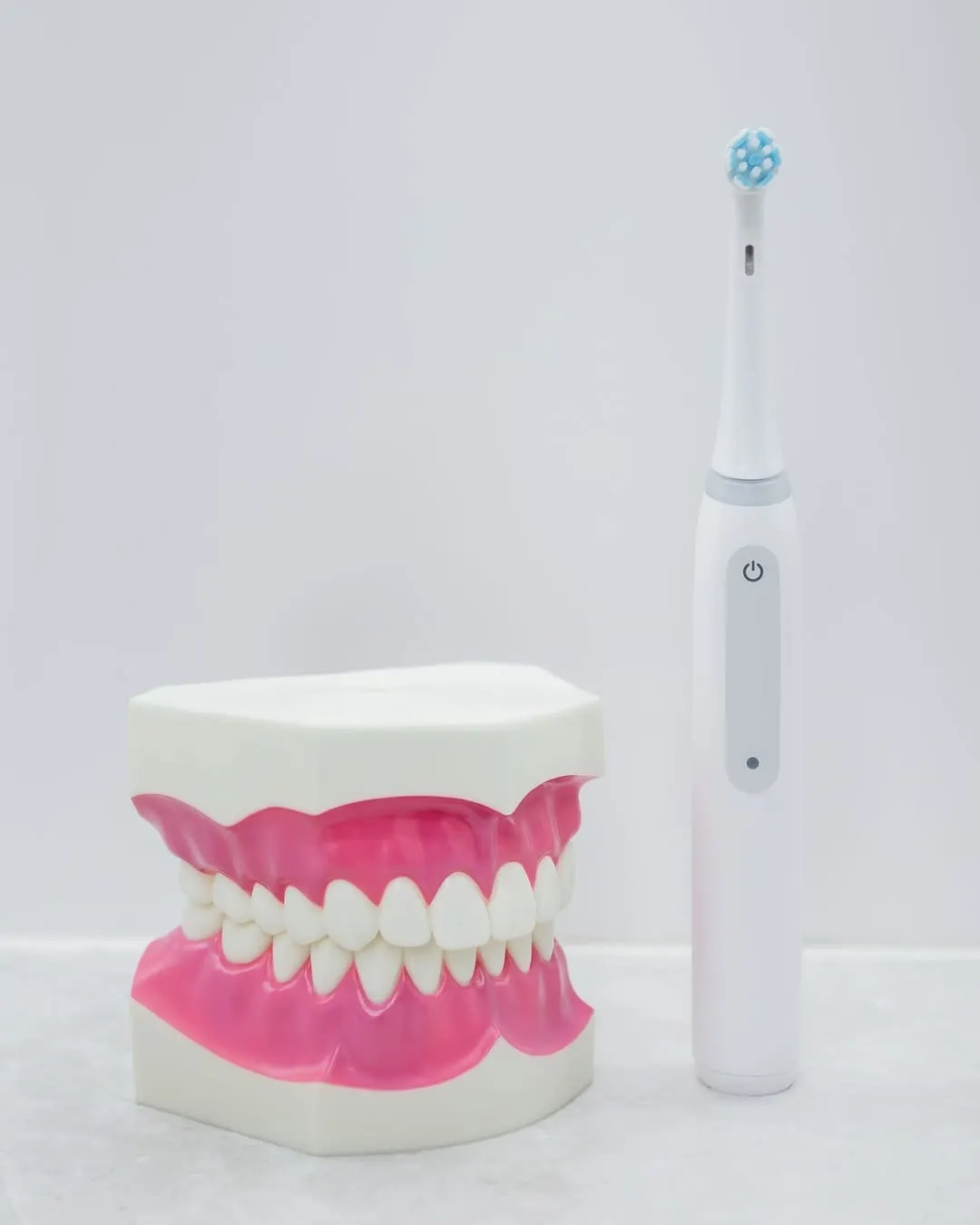 A model of a full set of teeth beside an electric toothbrush