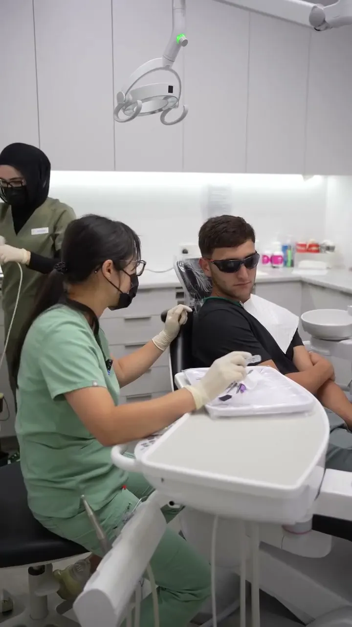 Dr Amanda Zhong preparing instruments beside a patient in the dental chair