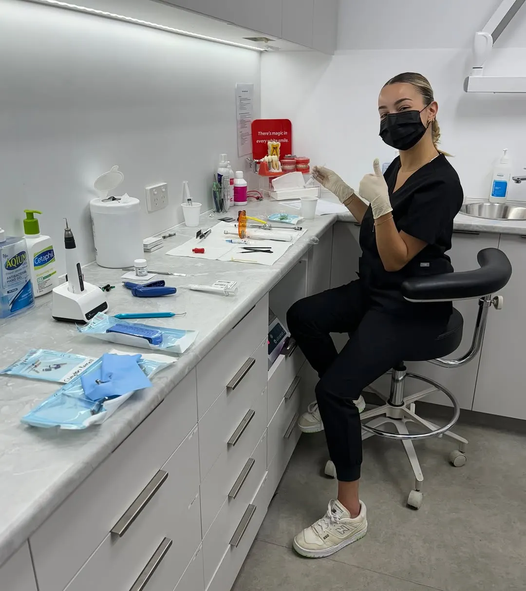 A dental assistant in a mask and gloves at the clinic prep bench
