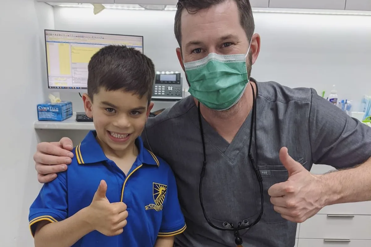 A boy giving a thumbs up with his dentist after his first visit