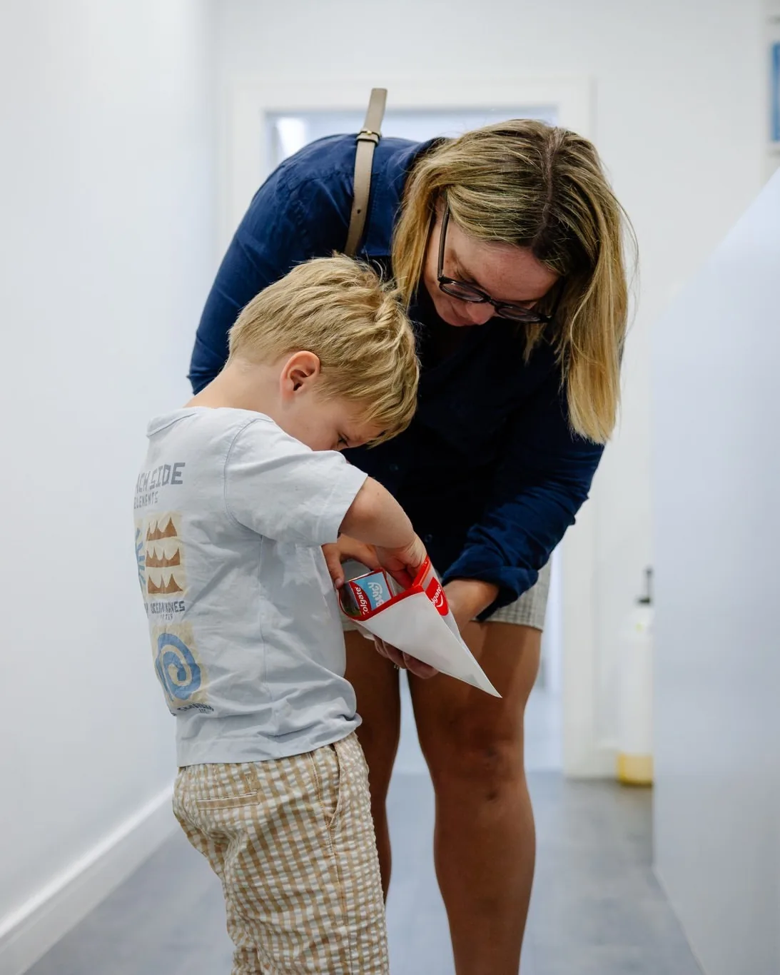 A boy and his mum looking into his dental care bag in the clinic hallway