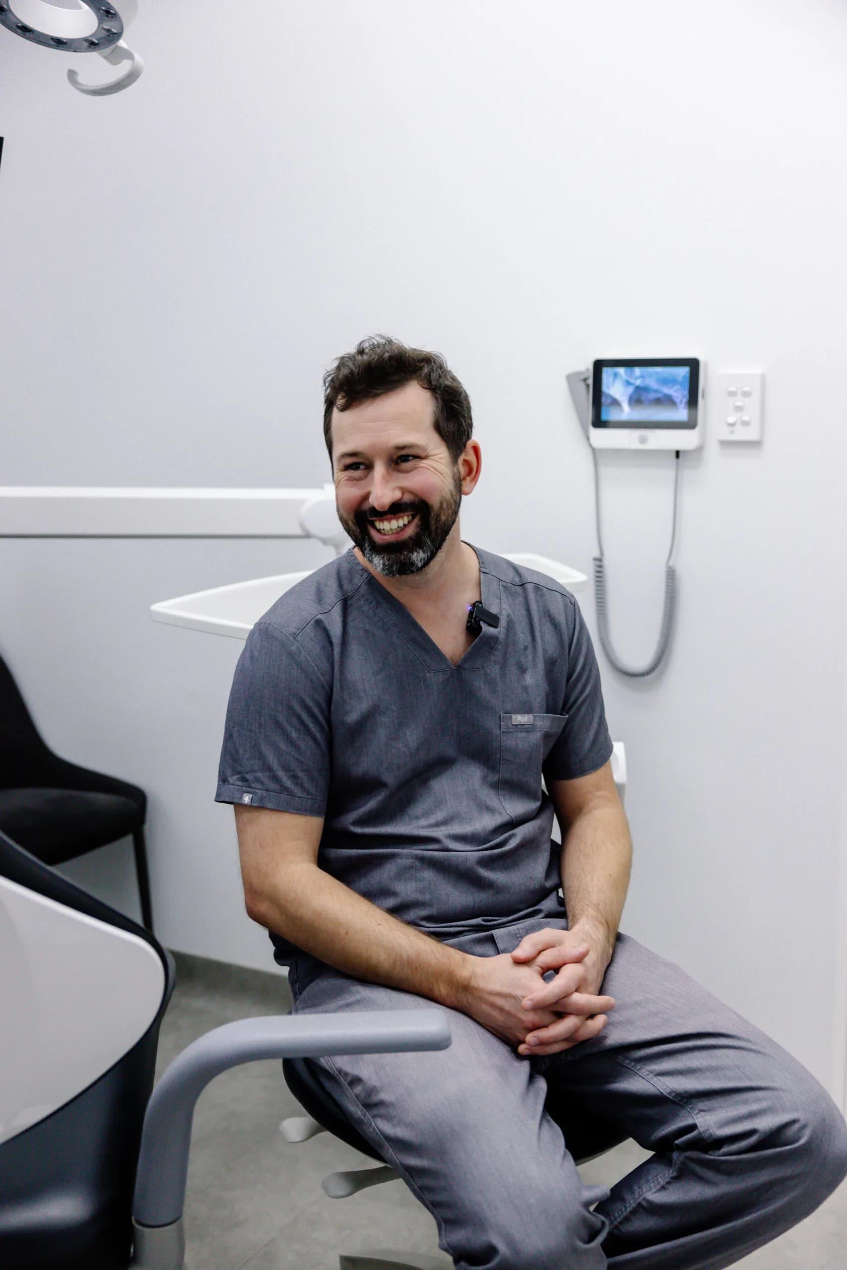 Dr James Pomfret in grey scrubs, laughing in the surgery